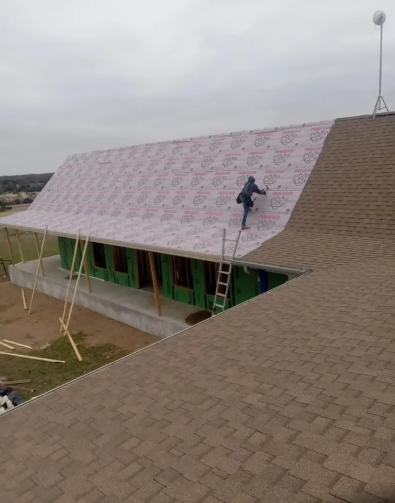 Worker preparing underlayment for a metal roof installation in Hobart